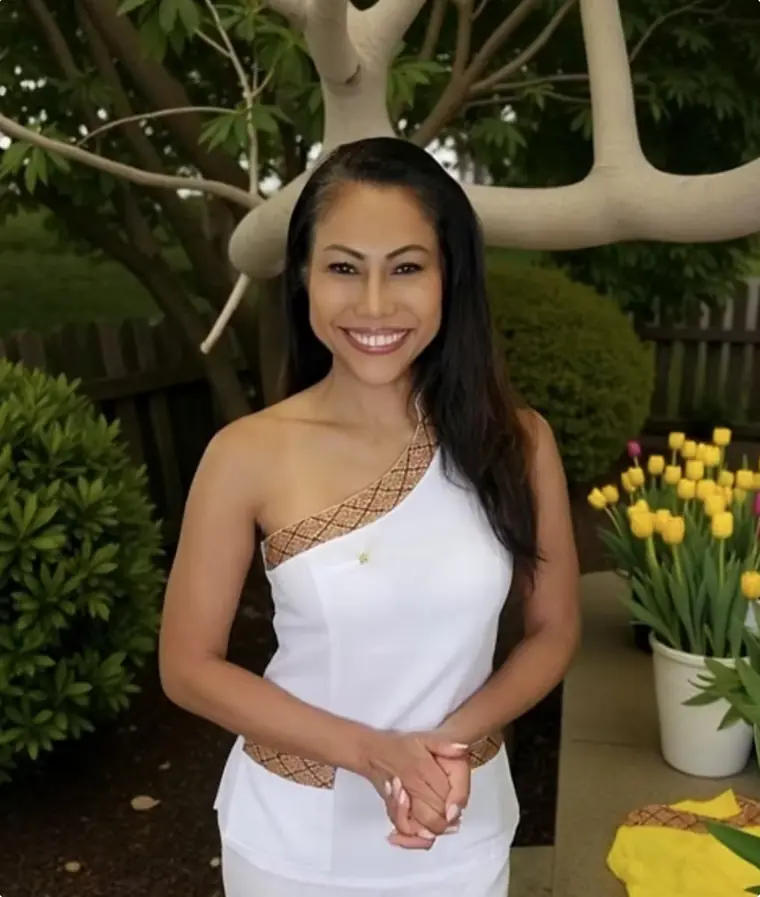 Phat, Gründerin von Chara Beauty Waxing, lächelnd in weisser Thai-Arbeitskleidung