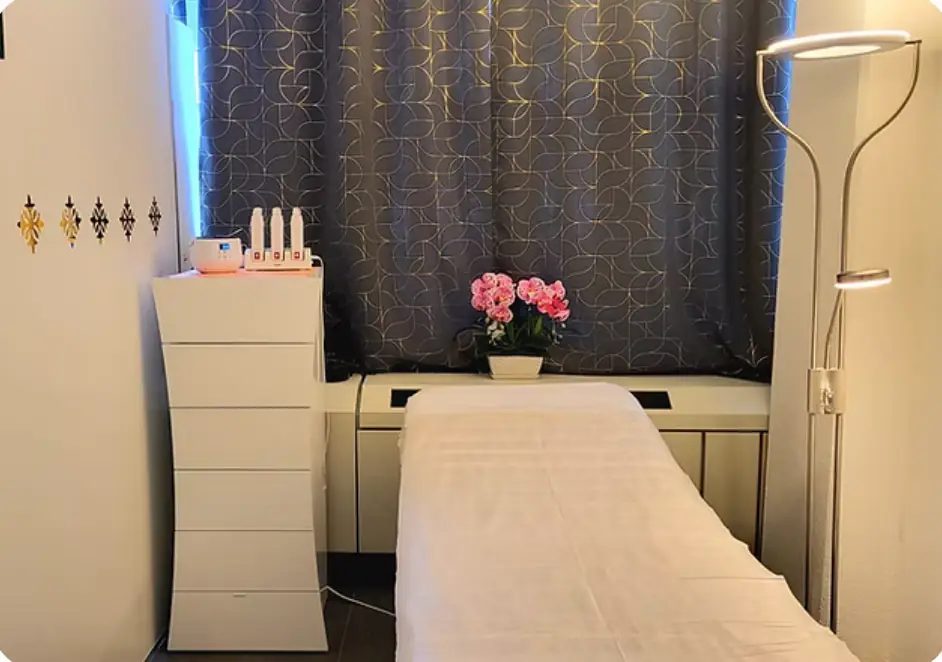 Behandlungsliege mit weissem Tuch, Orchideen und goldenen Thai-Ornamenten